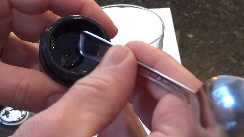 Scooping a pea-size glob of shilajit resin with a spoon handle